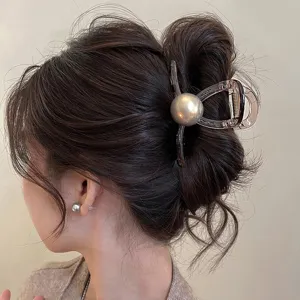 Vista dettagliata di molletta per capelli con perla grigia sullo chignon, accessorio elegante.