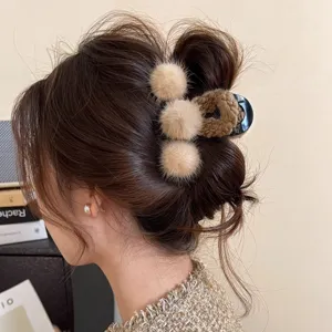 Fluffy plush hair claw clip for women, big winter hair accessory with cute fluffy pompoms.