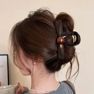 Vista dettagliata della molletta per capelli marrone scuro con fiocco, stile chic.