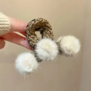 Autumn winter plush hair claw clip with fluffy pom poms, elegant brown knitted hair accessory.
