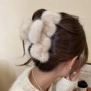 Detalle en primer plano de una pinza de pelo de peluche beige grande, accesorio de invierno.