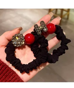 Close-up of black elastic hair band with rhinestones, red pearls and chic letter charm.