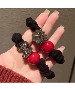 Detailed view of the elegant red pearl and sparkling rhinestone black hair scrunchie.