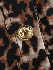 Détail exquis d'un gilet léopard pour femme avec boutons dorés tête de lion de luxe.