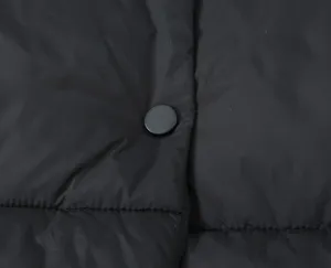 Black padded vest detail close-up showcasing quilted texture and snap button design