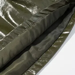 Primer plano detallado de prenda de charol brillante, textura arrugada y forro.