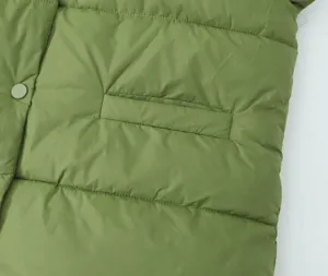Green quilted puffer vest detail close-up, showing pocket design and soft padded texture.