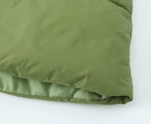 Green quilted puffer vest detail fabric texture view, soft winter outerwear material.
