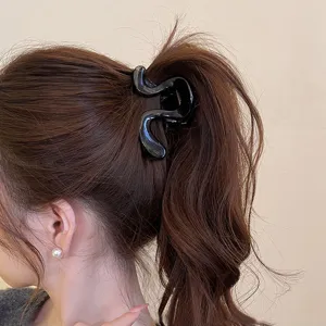 Vista dettagliata di un elegante fermaglio per capelli nero ondulato indossato, accessorio chic.