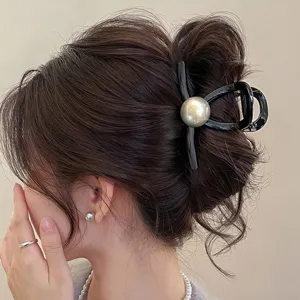 Vista dettagliata di un'elegante molletta per capelli nera con grande perla grigia.