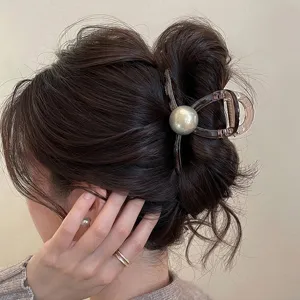 Primo piano del fermaglio per capelli con perla grigia indossato sullo chignon elegante.