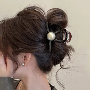 Primo piano di un elegante fermacapelli con perla grigia e resina marrone per acconciature raccolte.