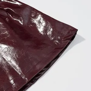 Primer plano de detalles de cuero arrugado brillante burdeos para ropa de mujer elegante.
