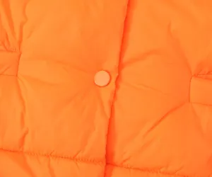 Close-up detail of women winter orange quilted cotton vest featuring snap button and soft fabric.
