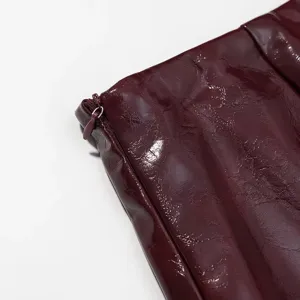 Primer plano de ropa de charol burdeos con cremallera, textura elegante y diseño chic.