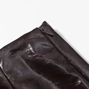 Primer plano de prenda de piel sintética brillante con textura visible y cremallera.