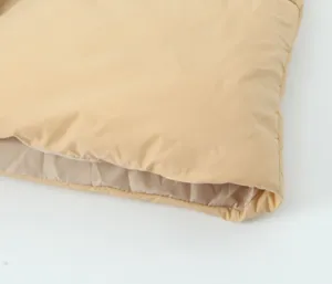 Close-up of khaki winter padded vest fabric and hem, soft texture and fine quilting detail.