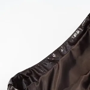 Primer plano detallado de tela de cuero marrón brillante con elegante textura plisada.