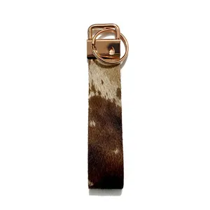 Close-up detail of cowhide wristlet keychain with rose gold hardware, western vintage style.