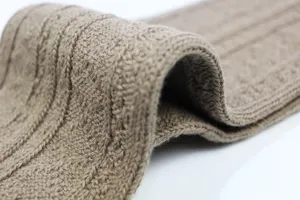 Close-up of thick cable knit over-the-knee socks, showing textured winter fabric detail.