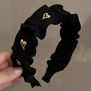 Detailaufnahme des eleganten schwarzen gerafften Haarreifs mit schicken goldenen Herzchen.