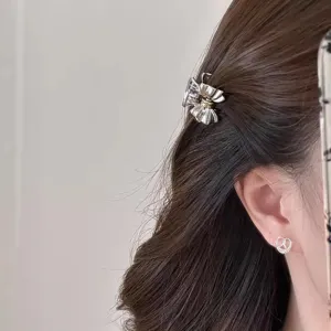 Scatto di dettaglio della pinza per capelli in metallo con fiocco, stile elegante e lucido.