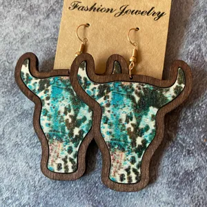 Gros plan détaillé des boucles d'oreilles en bois tête de taureau style western turquoise.