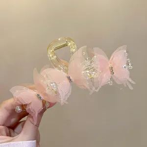 Nahaufnahme einer rosa Schmetterling-Haarklammer mit zarten Perlen und funkelnden Strasssteinen.