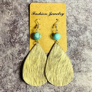 Détail en gros plan de boucles d'oreilles vintage en cuir avec perles de turquoise.