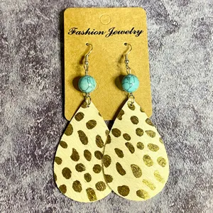 Gros plan sur les boucles d'oreilles avec perle turquoise et texture cuir imprimé léopard.
