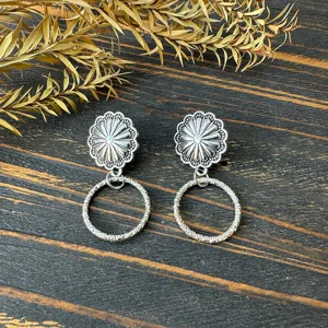 Detailed close-up shot of retro western metal earrings featuring a sunflower stud and textured drop hoop.