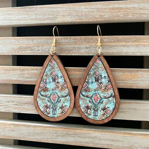 Detailed shot of Western vintage Aztec wooden teardrop earrings with bull skull pattern.
