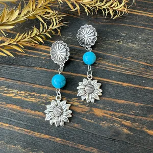 Detailed shot of Western style vintage metal sunflower and turquoise dangle earrings.