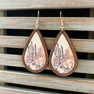 Detailed close-up of western retro wooden teardrop earrings with cowgirl and cactus print.