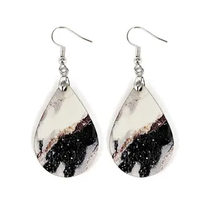 Close-up detail view of lightweight teardrop wooden earrings featuring abstract marble wave print.