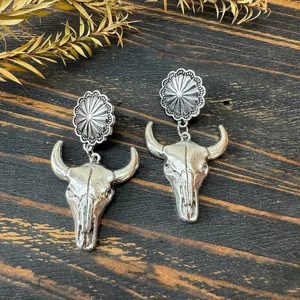 Vintage Western metal earrings featuring sunflower studs and bull skull pendants.