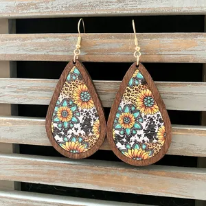 Close-up detail of western vintage wooden teardrop earrings with sunflower and aztec prints.
