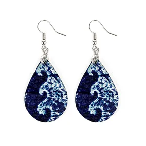 Detailed close-up of lightweight teardrop wooden earrings featuring blue tie-dye print.