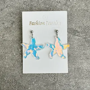 Detailed view of holographic starfish acrylic earrings showing sparkling texture on display card.
