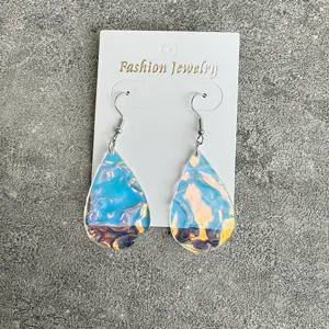 Detailed view of blue acrylic teardrop ocean wave earrings displayed on a white card.