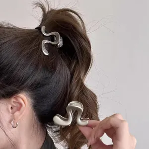 Detailansicht einer stilvollen silbernen wellenförmigen Haarklammer für elegante Frisuren.