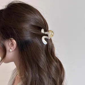 Nahaufnahme einer stilvollen Azetat Haarklammer mit welligem Design im braunen Haar getragen.