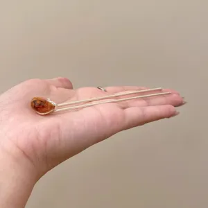 Close up of minimalist U shaped hair pin detail with amber style stone for vintage wear.