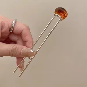 Close-up detail shot of traditional Chinese style U-shaped hair stick with amber stone.