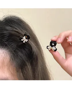 Detail close-up of small black rhinestone bow hair claw clip for chic bangs and broken hair
