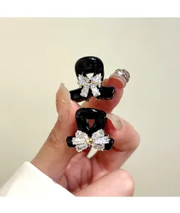 Mini black hair claw clip featuring a sparkling rhinestone bow, elegant and compact hair accessory.