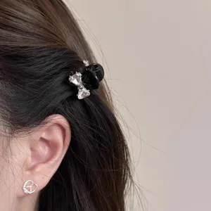 Detailaufnahme einer kleinen schwarzen Haarklammer mit Schleife und Strass für halbes Haar.
