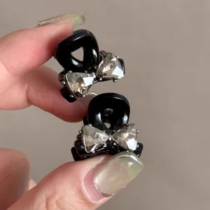 Kleine schwarze Haarklammer mit Strass Schleife Design für elegante Damen Frisuren im Alltag.