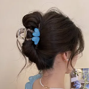 Detailaufnahme einer stilvollen blauen Herz Haarklammer im Haar, perfektes Alltagsaccessoire.