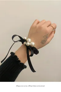 Elegante zwarte satijnen lint parel haarscrunchie strik armband detail weergave.